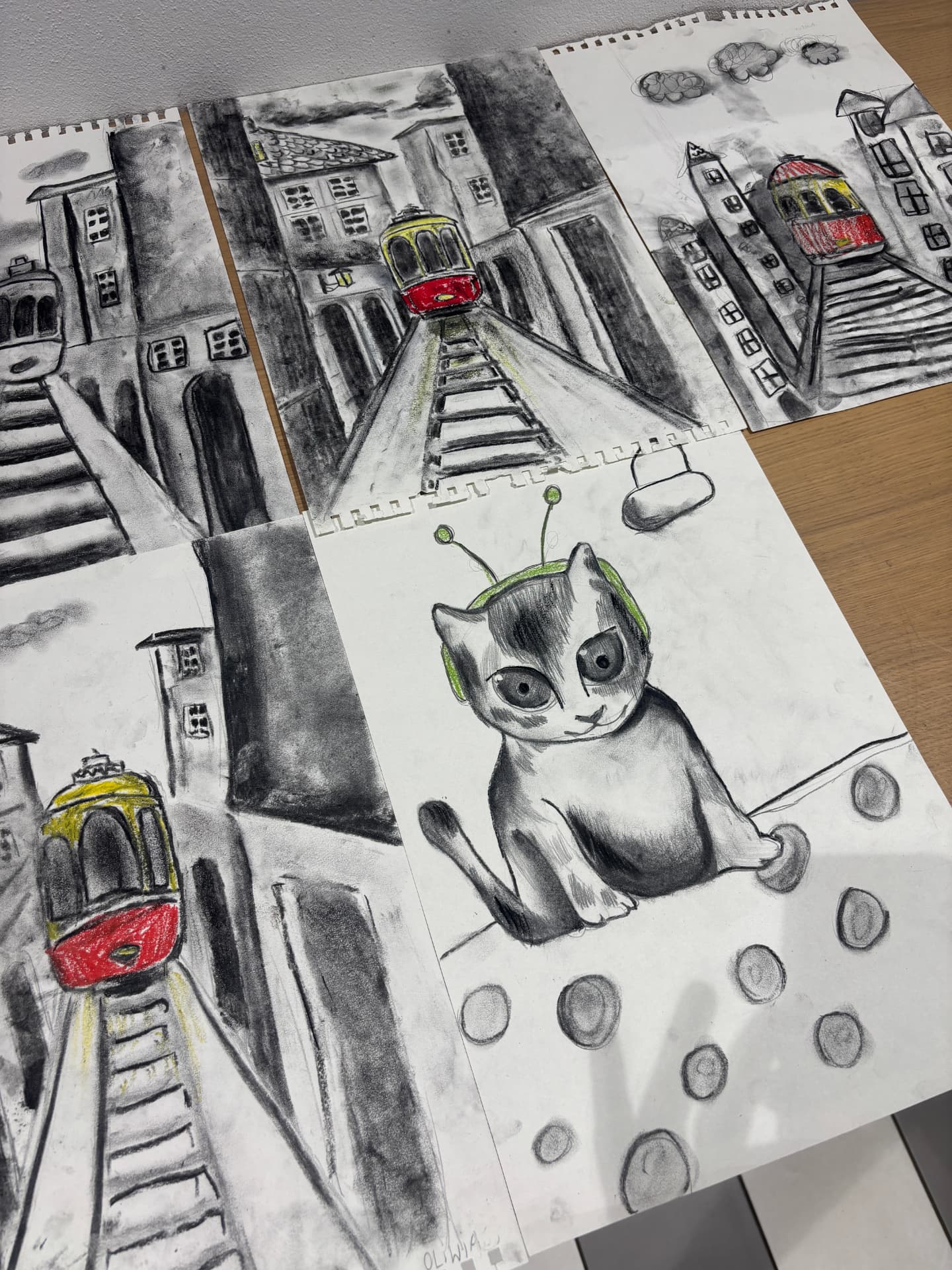 Rysunki węglem — tramwaje i portret kota na stole w pracowni